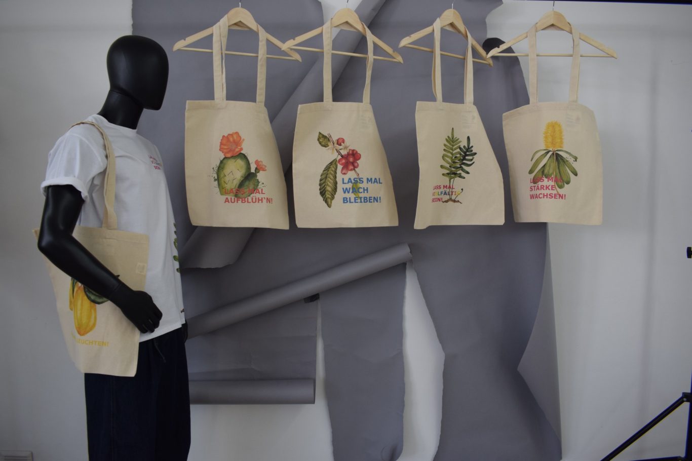 Totebags. ready-to-wear Kollektion Mannequin trägt eine Tasche, daneben vier Einkaufstaschen mit bunten Designs.