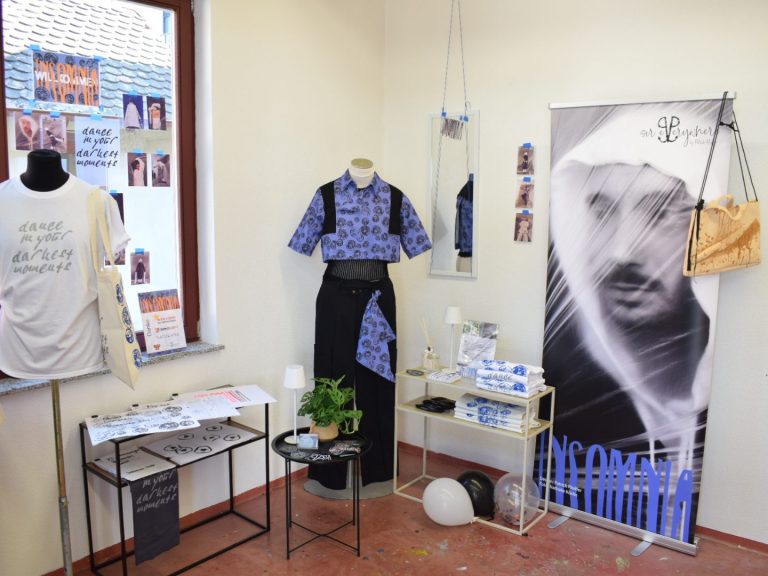 Verkaufsfläche / Ausstellung Insomnia Ein Ausstellungsraum mit Kleidung, Postern und Pflanzen.