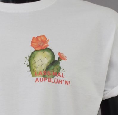 Weißes T-Shirt mit Kaktusmotiv und dem Schriftzug „Lasst mal aufblüh’n!“ in bunten Farben.