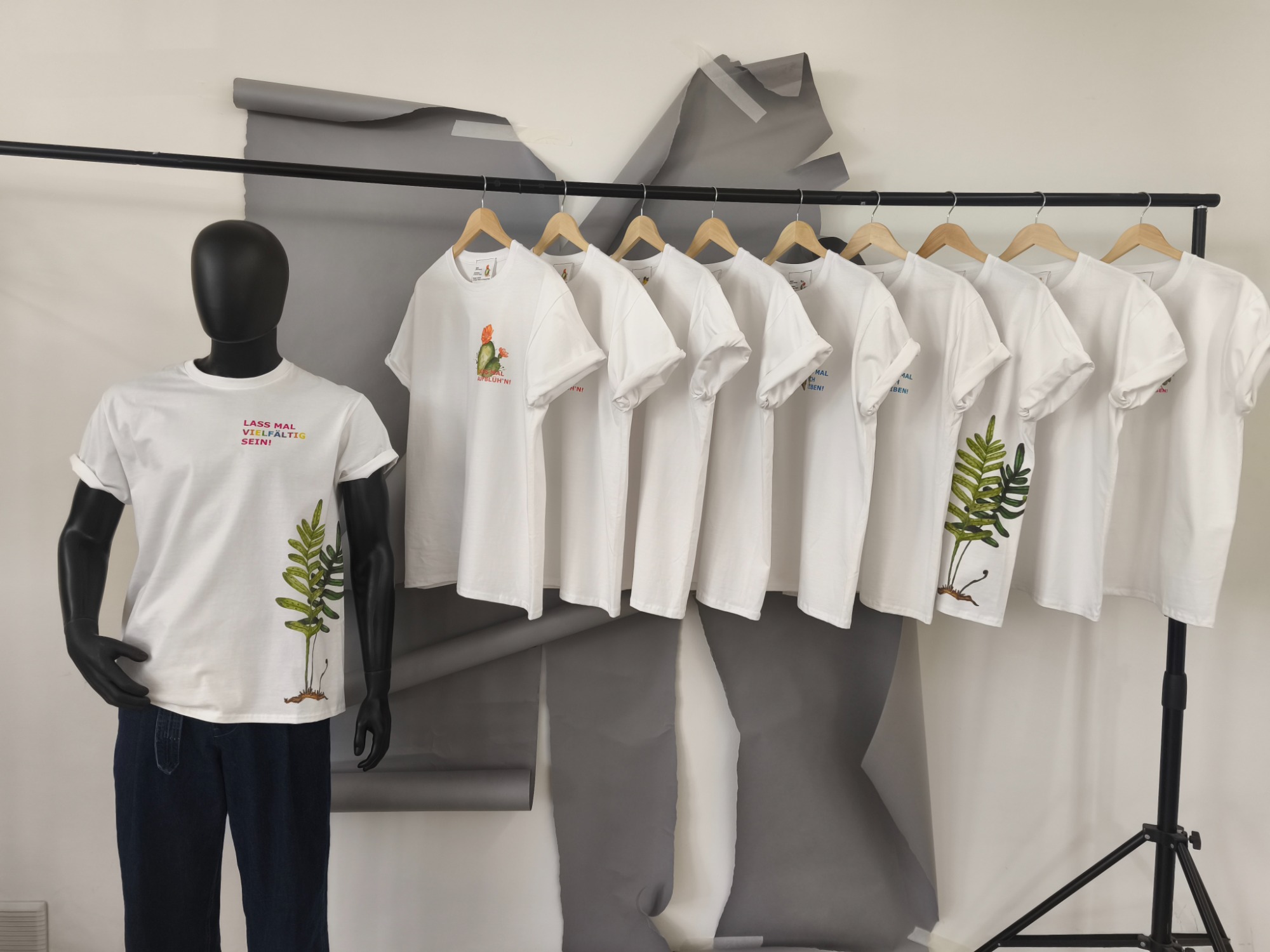 Shirts. ready-to-wear Kollektion Weißes T-Shirt mit Digitaldruck, präsentiert an einem schwarzen Mannequin und weiteren Shirts.